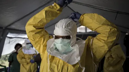Una trabajadora sanitaria se coloca su equipo de protección individual (EPI) antes de entrar en un centro de tratamiento del ébola gestionado por la Alianza para la Acción Médica Internacional (ALIMA) el 12 de agosto de 2018 en Beni.
