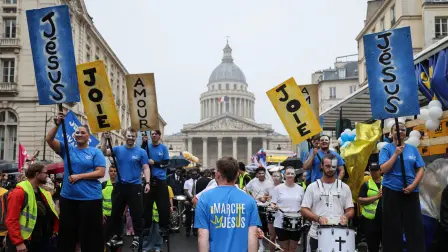 Durante la Marcha por Jesús, un evento cristiano, la gente camina sobre zancos frente al Panteón de París.