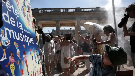 Los peatones se refrescan bajo un rociador de agua instalado por el Ayuntamiento de París durante la 45.ª edición de la Fiesta de la Música.
