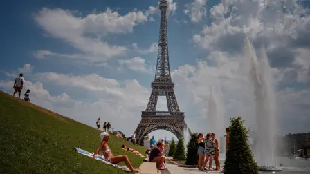 Personas se refrescan cerca de la fuente del Trocadero, con la Torre Eiffel de fondo.