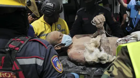 Equipos de rescate trasladan a una persona tras haberla sacado con vida de entre los escombros de un edificio colapsado.