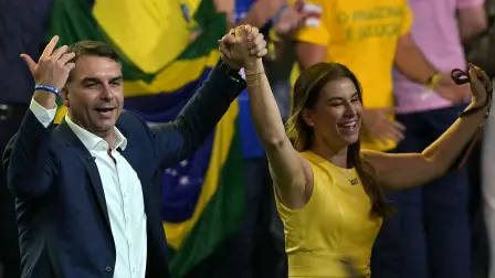 El aspirante presidencial derechista de Brasil, Flavio Bolsonaro, saluda junto a su esposa, Fernanda Bolsonaro, durante el lanzamiento de su candidatura en la convención del Partido Liberal (PL).