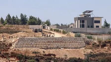 Soldados israelíes montan guardia junto a colonos frente a viviendas palestinas en la localidad de Qusra, al sur de Nablus, en la Cisjordania ocupada.