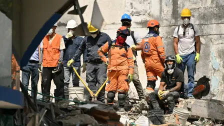 Equipos de rescate permanecen entre los escombros de un edificio colapsado.