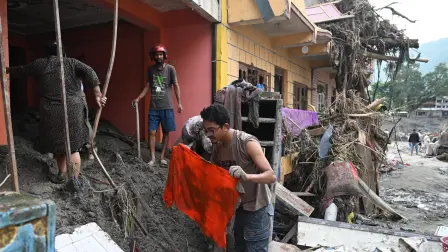 Personas recuperan materiales aprovechables de sus viviendas anegadas por el lodo tras unas inundaciones repentinas en Devighat.