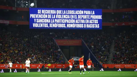 Una pantalla gigante despliega un mensaje antidiscriminación dentro de un estadio.