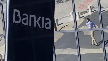 A man is seen reflected in the glass building of the Bankia bank headquarters in Madrid, Wednesday May 9, 2012. New bank president Jose Ignacio Goirigolzarri took over the troubled bank Wednesday after former conservative economy minister for Spain and former managing director for the International Monetary Fund, Rodrigo Rato resigned. Prime Minister Mariano Rajoy dodged a question on whether the government planned to nationalize troubled lender Bankia, Spain