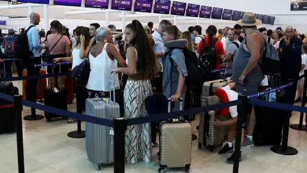 Tourists queue up in a check-in service at Cancun International Airport after Thomas Cook, the world