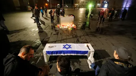 An Israeli flag is seen in front of lit candles at central market square in Halle