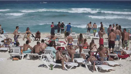 Spring breakers lay on the beach in Cancun