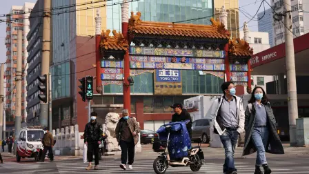 FILE PHOTO: People wearing face masks cross a street in Beijing, following outbreaks of the coronavirus disease (COVID-19) in China