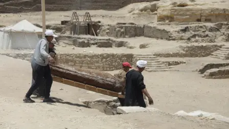 Workers carry a sarcophagus from newly discovered burial site, in Giza