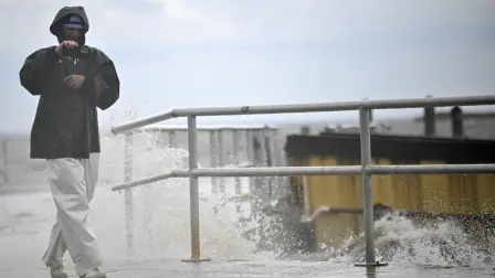 Un hombre usa su teléfono mientras las olas rompen contra la costa antes de la llegada del huracán Helene en Cedar Key, Florida.