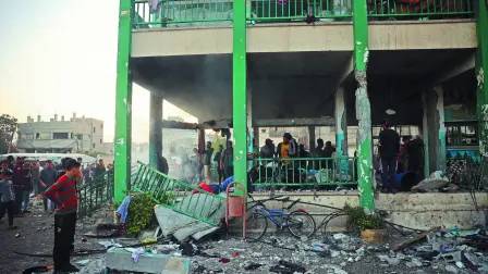 Palestinos observan una escuela destruida por Israel en el campo de refugiados Nusseirat.