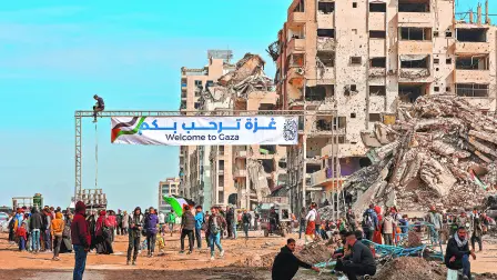 Palestinos se reúnen con una pancarta que da la bienvenida a las personas que cruzan desde el corredor Netzarim bloqueado por Israel.