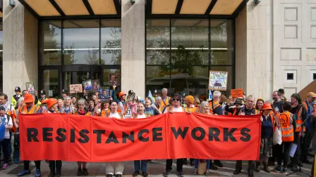Activistas climáticos de Just Stop Oil (JSO) posan para una foto afuera del Shell Centre, detrás de una gran pancarta.