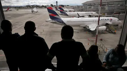 Pasajeros venezolanos observan los aviones de LATAM en la pista mientras esperan noticias tras la cancelación de su vuelo a Caracas en el Aeropuerto Internacional El Dorado, Bogotá, Colombia.
