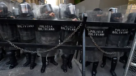 La policía antidisturbios de Bolivia vigila una de las entradas de la Plaza Murillo, mientras simpatizantes de Evo Morales protestan a favor de él.