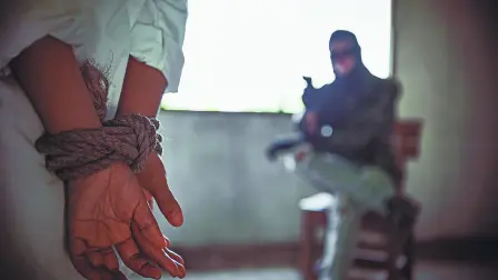 Back view of hostage woman with tie rope in hands,The thief pointed his gun towards him.