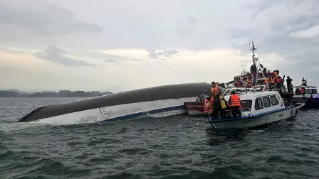 Personal de rescate reunido alrededor de un barco turístico volcado.