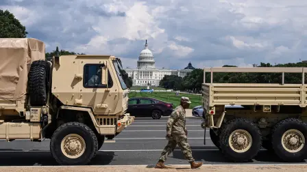 Un miembro de la Guardia Nacional deEU pasa junto a vehículos militares en el National Mall de Washington, DC.