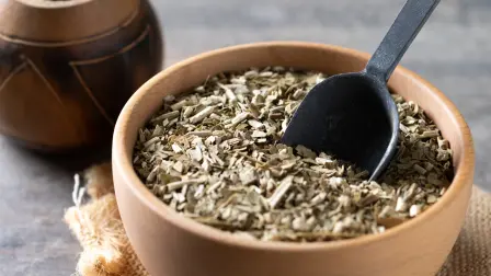Traditional yerba mate in bowl on wooden table