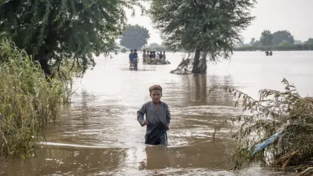 Un niño de siete años se abre paso a través de aguas de inundación hasta la altura de la cintura en Punjab, Pakistán.