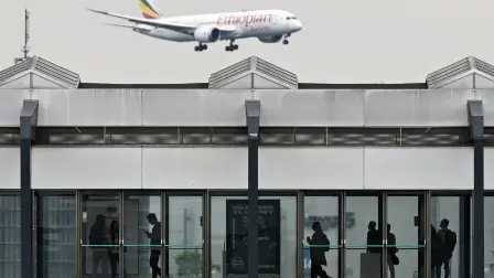 People wait for a train at a metro station as an Ethiopian Airlines Boeing 787-8 passenger plane flies in the sky during landing at the Copenhagen Airport in Copenhagen, Denmark, on June 4, 2025. (Photo by Sergei GAPON / AFP)