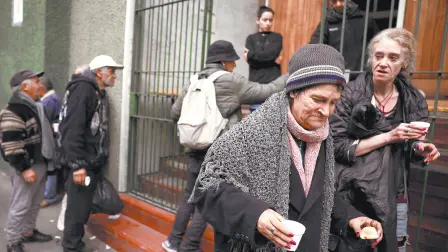 A woman walks away after receiving an afternoon snack from a church that helps the poor, as other people line up, in Buenos Aires, Argentina, May 31, 2024.