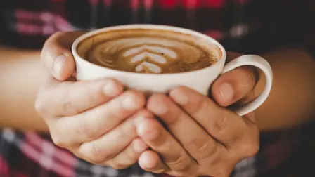Closeup hand of female holding a coffee cup in the cafe add the filter retro color tone, coffee drinking concept.
