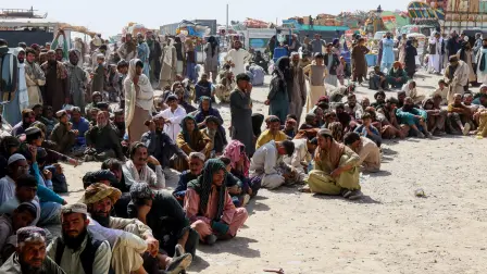 Ciudadanos afganos esperan para registrarse mientras intentan regresar a su país, con camiones cargados con sus pertenencias al fondo, después de que Pakistán cerrara los cruces fronterizos para el comercio con Afganistán.