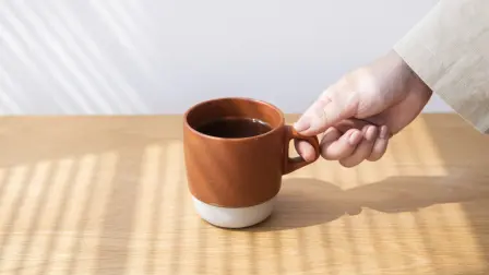 Woman getting a coffee cup from a wooden table