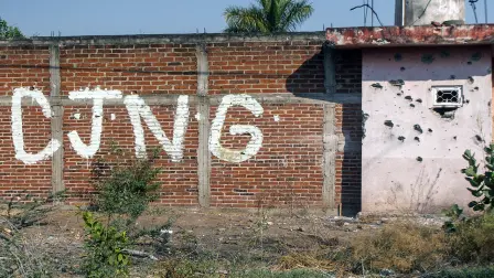 View of a bullet-riddled wall bearing the initials of the criminal group Cartel Jalisco Nueva Generacion (CJNG) at the entrance of the community of Aguililla, state of Michoacan, Mexico, on April 23, 2021. The municipality of Aguililla is being threatened due to the confrontation of organized crime groups called the Jalisco Nueva Generacion Cartel (CJNG) and the Michoacan Family (now called Viagras). (Photo by ENRIQUE CASTRO / AFP)