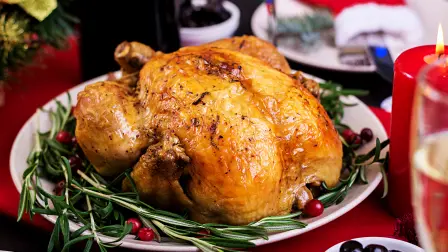 Baked turkey. Christmas dinner. The Christmas table is served with a turkey, decorated with bright tinsel and candles. Fried chicken, table.  Family dinner.