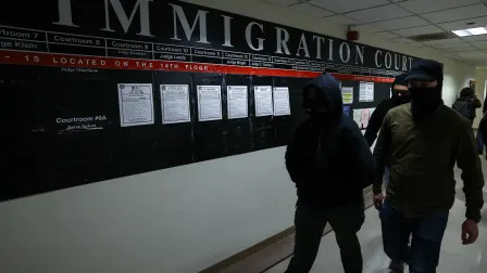 Masked federal agents walk in a hallway at the New York Federal Plaza Immigration Court inside the Jacob K. Javitz Federal Building in New York on December 22, 2025. US President Donald Trump has made deporting undocumented immigrants a key priority for his second term, after successfully campaigning against an alleged "invasion" by criminals. (Photo by CHARLY TRIBALLEAU / AFP)