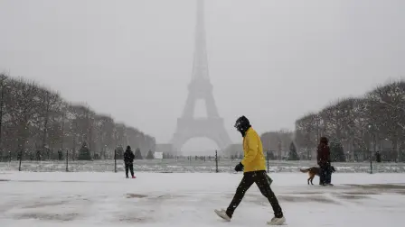 Peatones caminan por el Campo de Marte cubierto de nieve cerca de la Torre Eiffel.