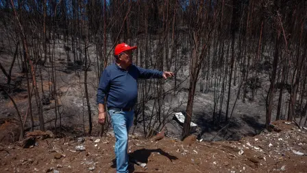 Jorge Cuadra shows a burnt area after the devastating forest fires that ravaged the region on January 3, in Punta de Parra, near Concepcion, Chile, on January 21, 2026. Police in south-central Chile have arrested a man on suspicion of starting one of the recent wildfires that killed 20 people and razed entire neighborhoods, the government said on January 21. (Photo by Raul BRAVO / AFP)