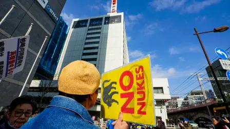 A participant taking part in a demonstration against the restart of the Kashiwazaki-Kariwa Nuclear Power Plant holds up a sign reading 