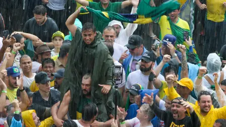 Brazilian Federal Deputy Nikolas Ferreira gestures among supporters of former President Jair Bolsonaro during a march in Brasilia on January 25, 2026. Deputy Ferreira and Bolsonaro's supporters arrived after walking the route between Paracatu, in Minas Gerais state, and the federal capital with the aim of drawing attention to the defense of amnesty for Bolsonaro and those convicted for the acts of January 8, 2023. (Photo by Sergio LIMA / AFP)