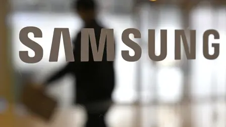 A man walks past the logo of Samsung Electronics displayed on a glass door at the company's Seocho building in Seoul on January 29, 2026. South Korean tech giant Samsung Electronics posted record quarterly profits on January 29, riding strong market demand for its artificial intelligence chips. (Photo by Jung Yeon-je / AFP)