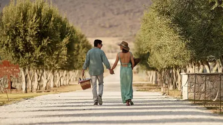 Pareja entre viñedos, cesta en mano: una escapada de San Valentín para brindar, saborear vinos y quesos, y coleccionar recuerdos.