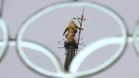 La estatua de la Virgen María en lo alto de la catedral gótica del Duomo se ve a través de los icónicos anillos de neón olímpicos antes de los próximos Juegos Olímpicos de Invierno de Milán-Cortina en Milán, Italia.