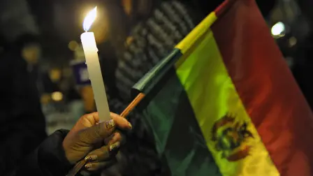 A woman holds a candle and a Bolivian national flag during a vigil in homage of victims of clashes between supporters of defeated presidential candidate Carlos Mesa and supporters of the ruling Movimiento Al Socialismo (MAS) party in La Paz, on November 1, 2019. President Evo Morales called Thursday for a 