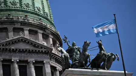 The sculpture La Cuadriga by the Italo-Argentine sculptor Victor de Pol is seen alonside the Argentinian national flag atop the National Congress building, where Argentina's President Javier Milei's labour reforms are being treated, in Buenos Aires on February 27, 2026. On February 27, the Argentine Senate also passed into law an initiative that reduces the age of criminal responsibility from 16 to 14, a bill promoted by President Javier Milei that the government celebrated as 