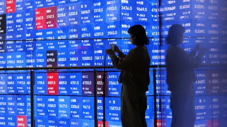 Un visitante se encuentra junto a una pantalla electrónica que muestra el tablero de cotización de los precios de las acciones Nikkei de Japón dentro de una sala de conferencias en Tokio, Japón.