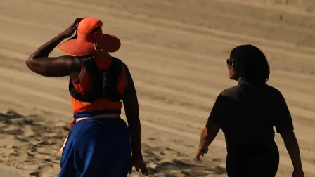 A person wears a hat for shade under the morning sun while walking along The Strand in Redondo Beach, California on March 20, 2026, during a heat wave. A record early heat wave striking the west of the United States on March 20 is a one-in-500-years type event and all but certainly the result of human-caused climate change, experts say. The heat has been toppling records this week and was set to continue into the weekend across western cities, expanding eastward. (Photo by Patrick T. Fallon / AFP)