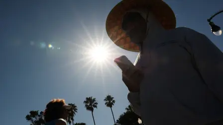 Una persona lleva un sombrero para protegerse del sol matutino mientras camina por The Strand en Redondo Beach, California.