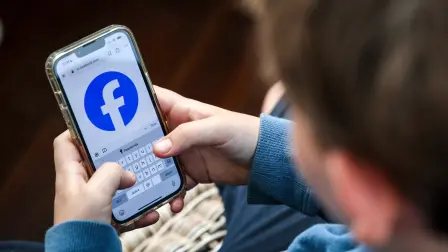 This photo taken on October 24, 2025 shows a 14-year-old boy posing at his home near Gosford as he looks at the Facebook page on his mobile phone. Popular social media website Reddit and streaming giant Kick will be added to a list of websites banned for under-16s in Australia from next month, Canberra said on November 5. Australia will from December 10 force social media platforms including Facebook, Instagram and Tiktok to remove users under the age of 16, slapping hefty fines of up to Aus$49.5 million (US$32 million) if they fail to do so. (Photo by David GRAY / AFP)