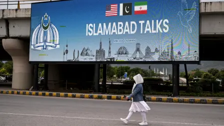 Una mujer pasa junto a una pantalla digital que muestra noticias sobre las conversaciones de paz entre Estados Unidos e Irán en una calle de Islamabad.