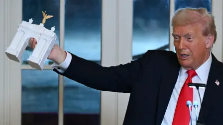 (FILES) US President Donald Trump holds up a model for a proposed "Independence Arch" as he speaks during a dinner with ballroom donors in the East Room of the White House in Washington, DC on October 15, 2025. The Trump administration unveiled plans on April 10, 2026 for a grand arch it intends to build in Washington, a new project by the American president designed to leave his mark on the US capital. "I am pleased to announce that TODAY my Administration officially filed the presentation and plans to the highly respected Commission of Fine Arts for what will be the GREATEST and MOST BEAUTIFUL Triumphal Arch, anywhere in the World," Trump wrote on his Truth Social platform. (Photo by ANDREW CABALLERO-REYNOLDS / AFP)